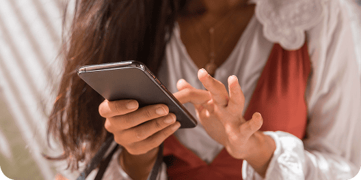 Mãos de uma mulher segurando um celular para compras online