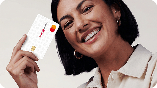 uma jovem mulher sorri com o cartão IOB Benefícios nas mãos